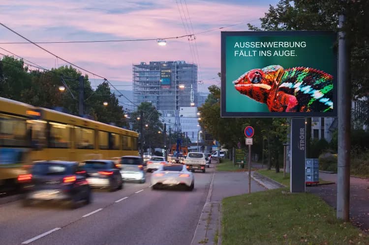 Digitale Außenwerbung in Stuttgart an einer Straße. Auf dem Display: Ein Chamäleon mit dem Claim darüber: "Außenwerbung fällt ins Auge."